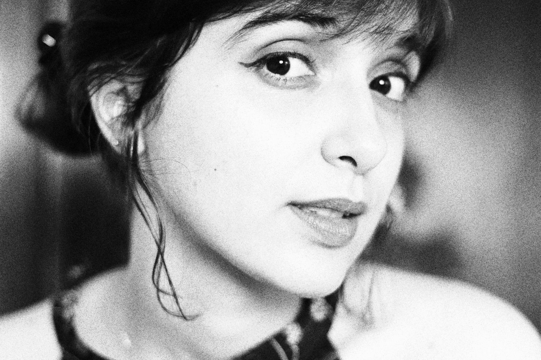 Beautiful woman with radiant flawless complexion, showcasing smooth skin and subtle makeup in a natural outdoor setting.