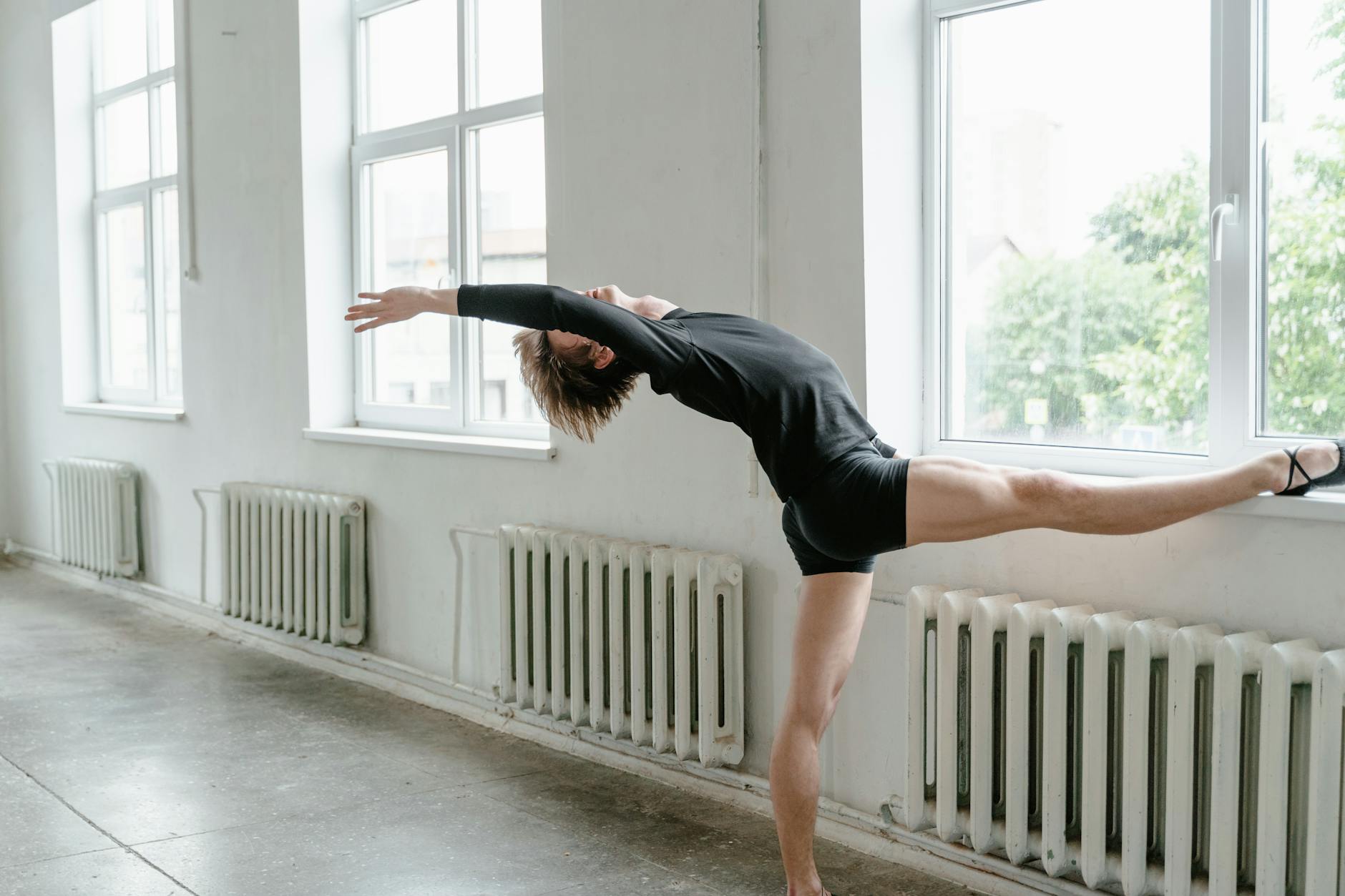 A fitness model performing a dumbbell shoulder press exercise with weights and a barbell in a gym setting to build stronger shoulders.